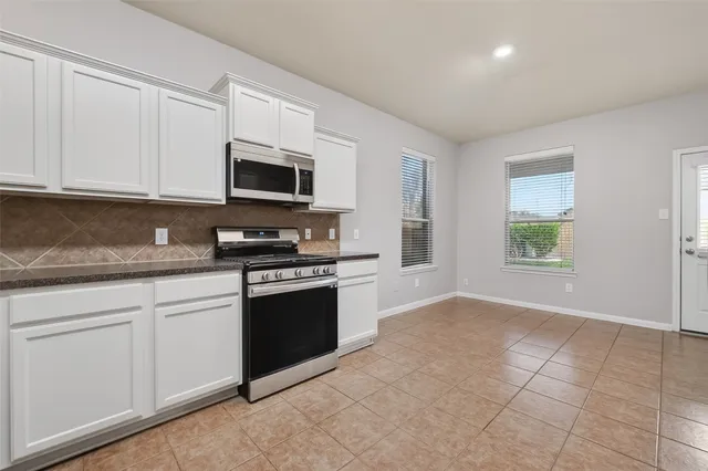 a kitchen with granite countertop a stove a microwave and a sink