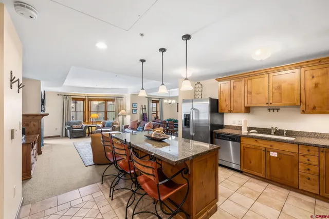 a kitchen with a stove a sink a dining table and chairs with wooden floor