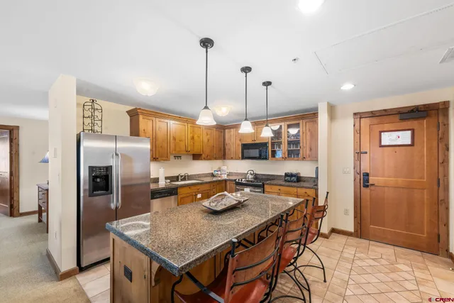 a kitchen with stainless steel appliances granite countertop a refrigerator a sink a stove and a wooden floors