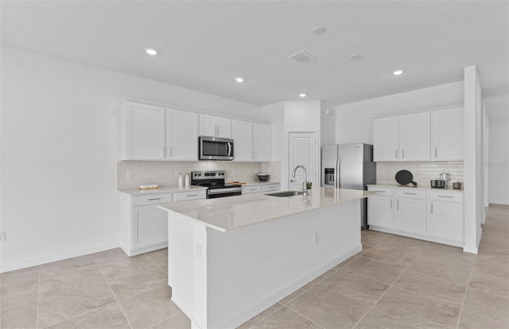 6909 Southwest 90th Place Ocala, FL 34476 - Photo 3 of 20 a kitchen with white cabinets and white appliances