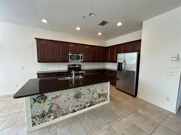 a kitchen with stainless steel appliances granite countertop a refrigerator and a stove top oven