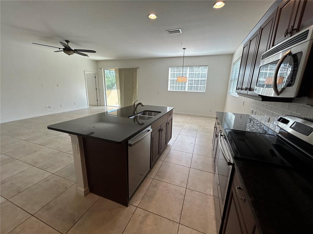 8143 Miramar Way, Unit 8143 Lakewood Ranch, FL 34202 - Photo 5 of 18 a kitchen with stainless steel appliances granite countertop a stove a sink and a microwave