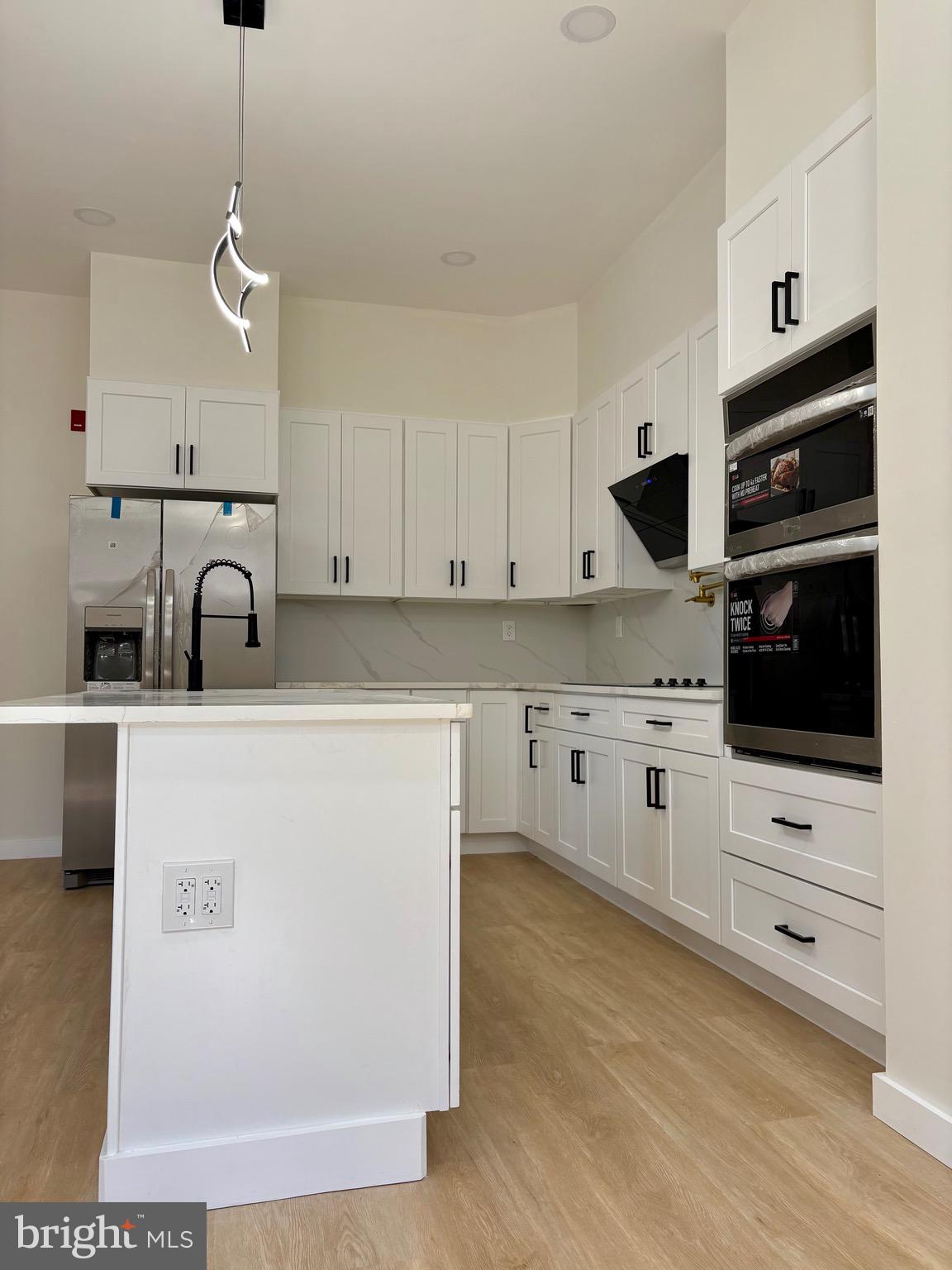 865 West Lancaster Avenue Bryn Mawr, PA 19010 - Photo 3 of 16 a kitchen with stainless steel appliances a stove a sink and white cabinets with wooden floor