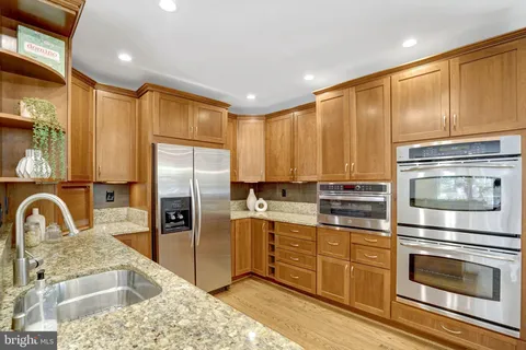 a kitchen with stainless steel appliances granite countertop a refrigerator a stove and a wooden floors