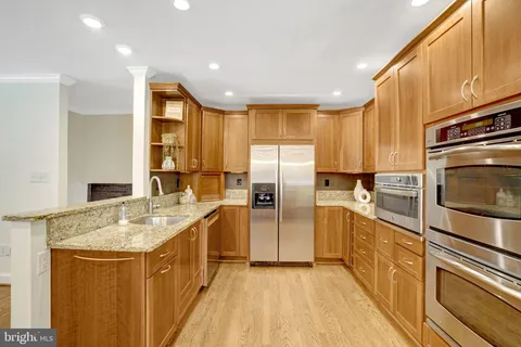 a kitchen with stainless steel appliances granite countertop a stove a refrigerator a kitchen island with a dining table and chairs with wooden floor