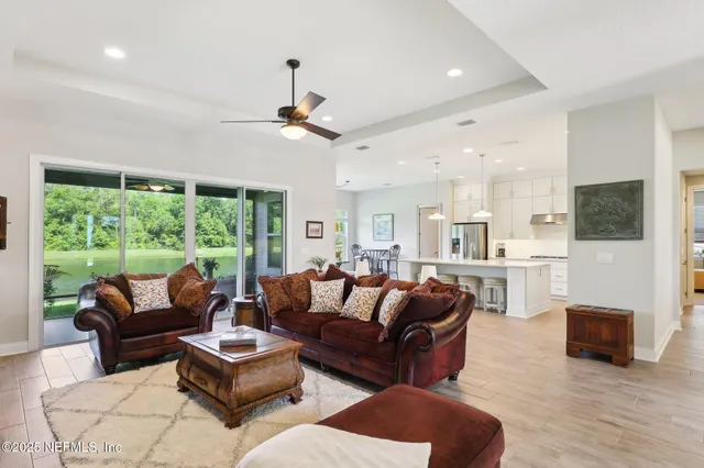a living room with furniture a ceiling fan and a large window
