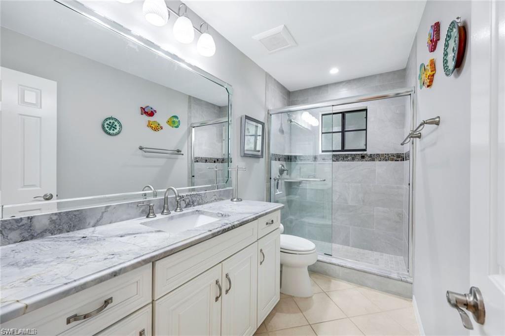 6555 Valen Way, Unit G201 Naples, FL 34108 - Photo 18 of 28 a bathroom with a granite countertop sink a toilet a shower and a mirror