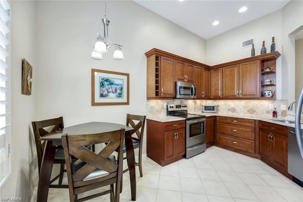 6555 Valen Way, Unit G201 Naples, FL 34108 - Photo 20 of 28 a kitchen with stainless steel appliances granite countertop a stove top oven a sink a dining table and chairs