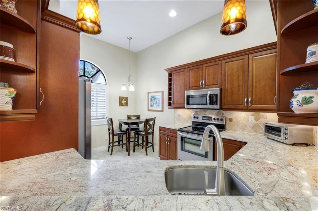 6555 Valen Way, Unit G201 Naples, FL 34108 - Photo 6 of 28 a kitchen with stainless steel appliances granite countertop a sink stove and microwave