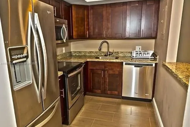 a kitchen with stainless steel appliances granite countertop a refrigerator a stove and a sink