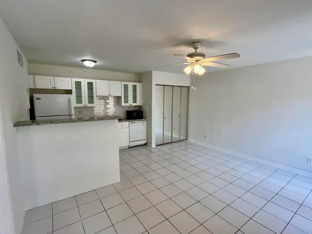 a kitchen with kitchen island granite countertop white cabinets and refrigerator