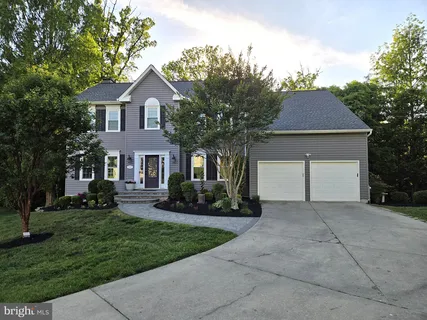 a front view of a house with a garden and trees