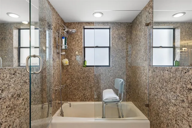 a bathroom with a bathtub a shower a sink and a window