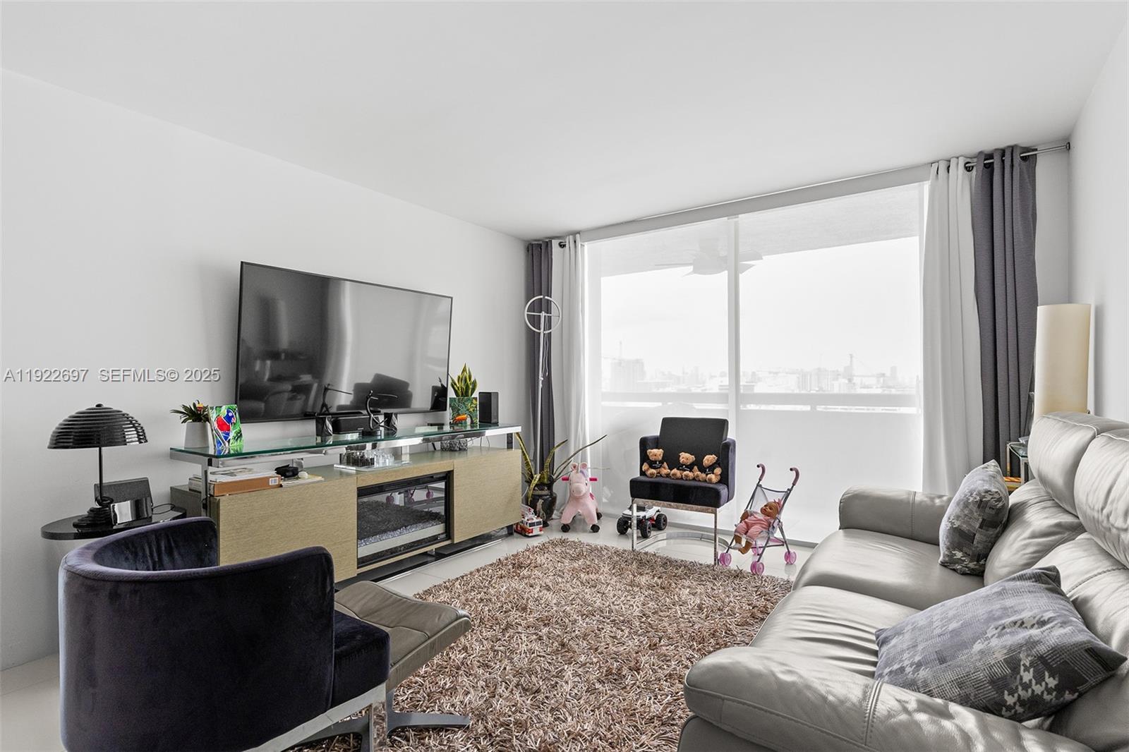 1775 Washington Avenue, Unit 14F Miami Beach, FL 33139 - Photo 5 of 25 a living room with furniture a large window and a flat screen tv