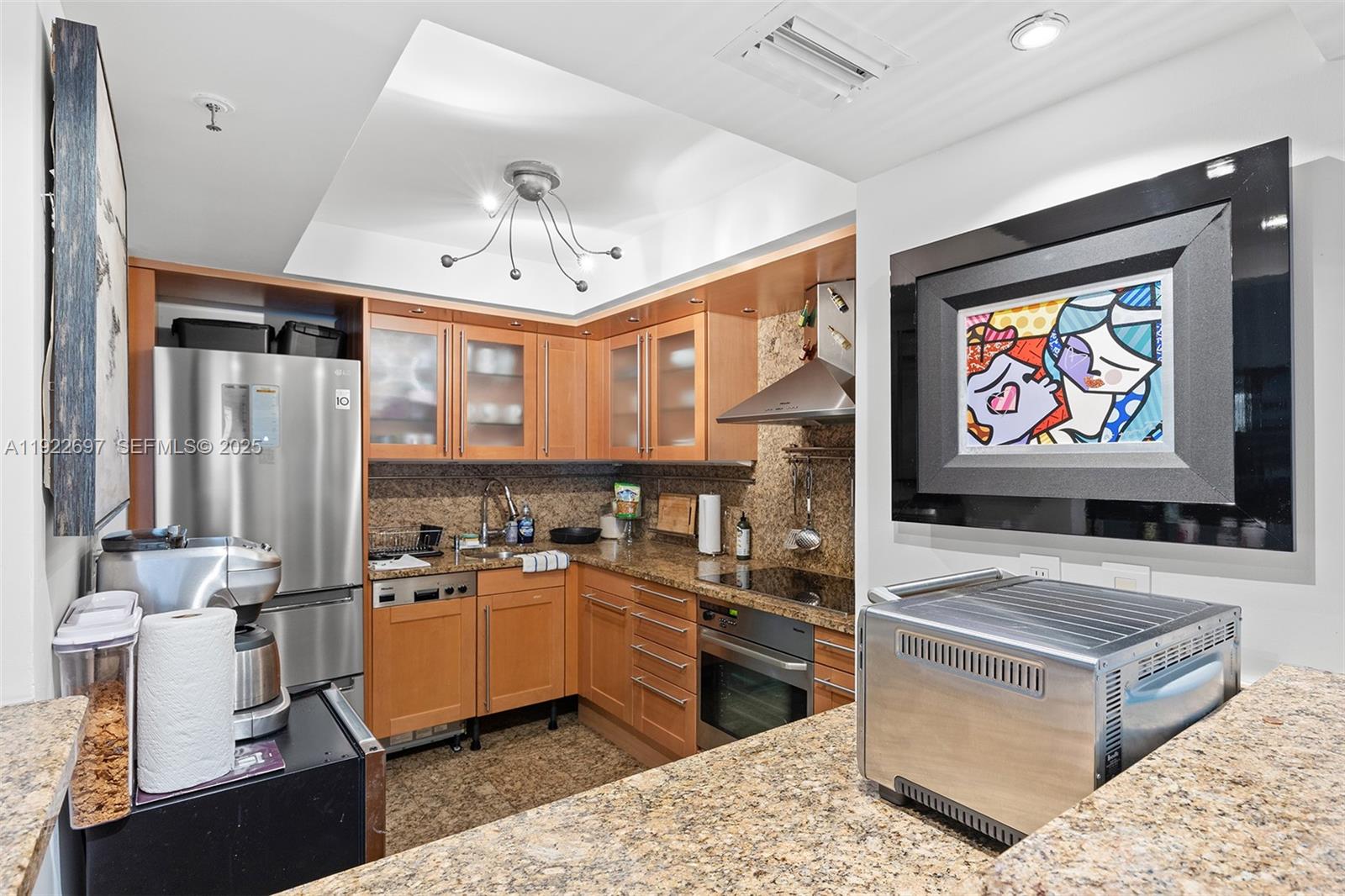 1775 Washington Avenue, Unit 14F Miami Beach, FL 33139 - Photo 9 of 25 a kitchen with stainless steel appliances kitchen island granite countertop a sink and a stove top oven