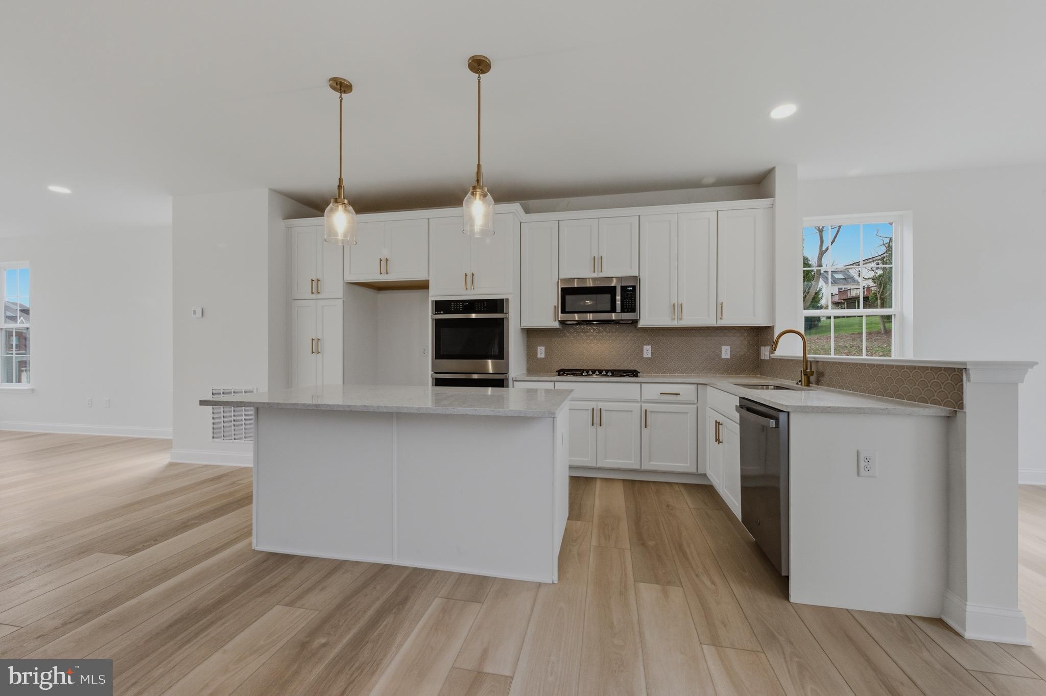253 Grove View Drive Hockessin, DE 19707 - Photo 5 of 25 a kitchen with stainless steel appliances granite countertop a stove a sink and white cabinets with wooden floor