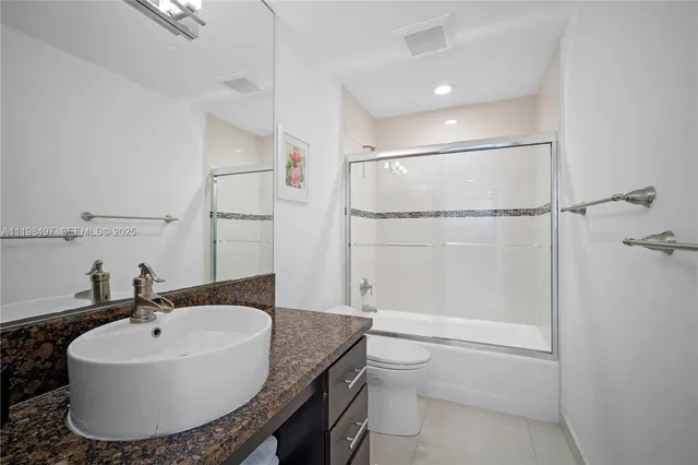 a bathroom with a granite countertop sink a mirror and shower