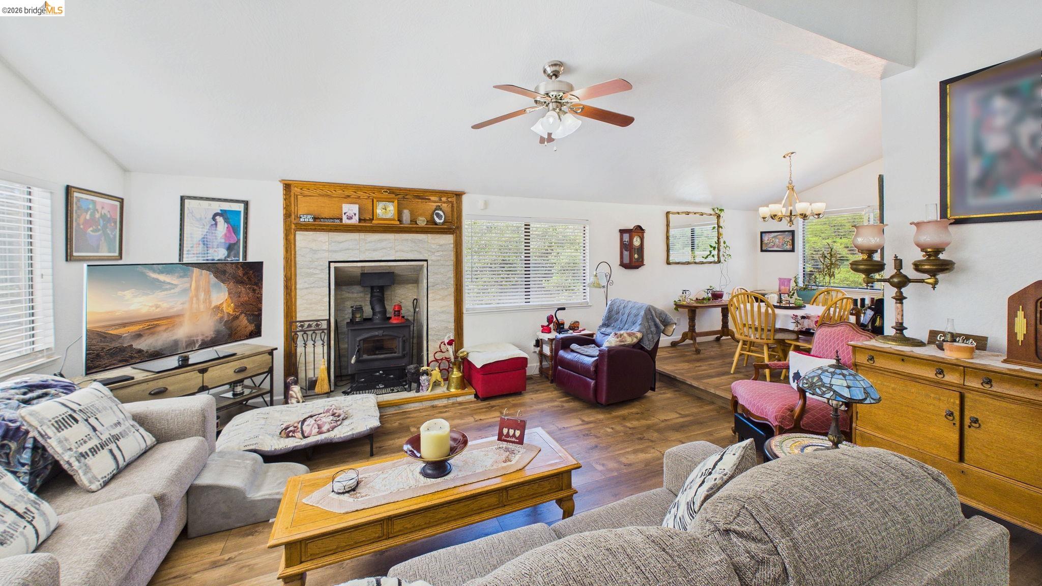 11858 Campo Seco Road Sonora, CA 95370 - Photo 35 of 45 Vaulted ceilings enhance the main living space, featuring wood-finish flooring and a fireplace with a wood-burning stove insert