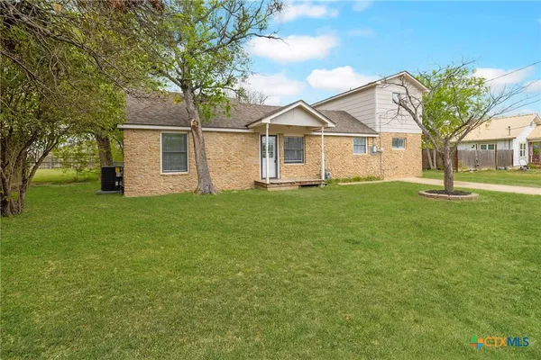 a view of a yard in front of a house with large trees