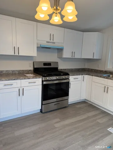 a kitchen with white cabinets stainless steel appliances and wooden floor