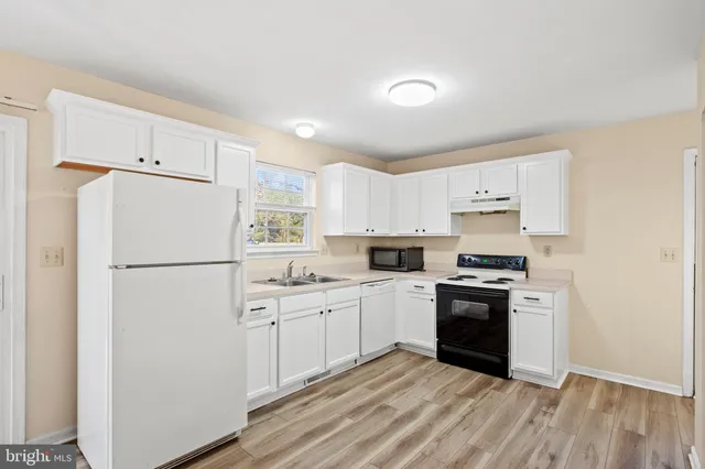 a kitchen with stainless steel appliances a refrigerator sink and white cabinets