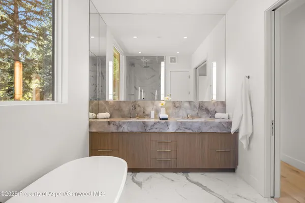 a spacious bathroom with a tub sink and mirror
