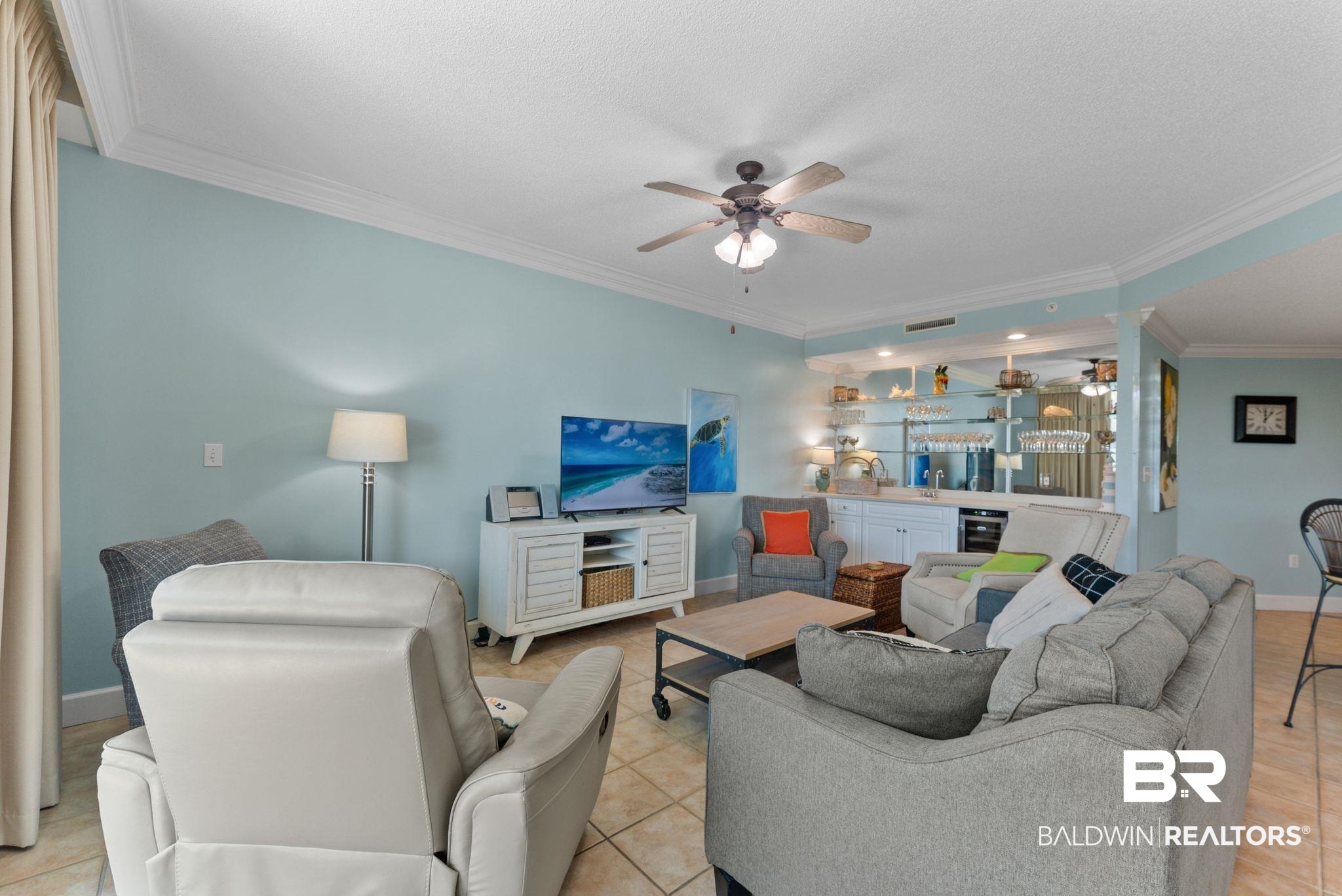 27580 Canal Road, Unit 1427 Orange Beach, AL 36561 - Photo 15 of 38 Living room with ornamental molding, wet bar, ceiling fan, light tile patterned floors, and a textured ceiling
