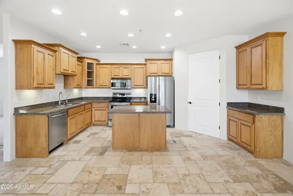 a kitchen with stainless steel appliances granite countertop a stove top oven a sink a dining table and chairs