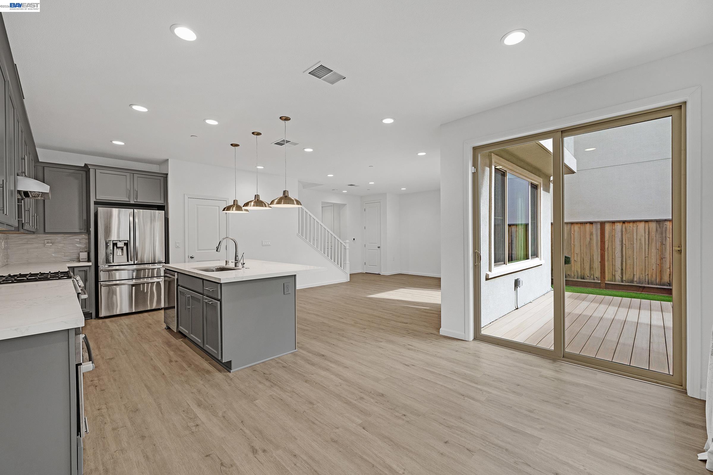 5990 Peridot Place Dublin, CA 94568 - Photo 12 of 43 a kitchen with stainless steel appliances kitchen island wooden floors wooden cabinets and entryway