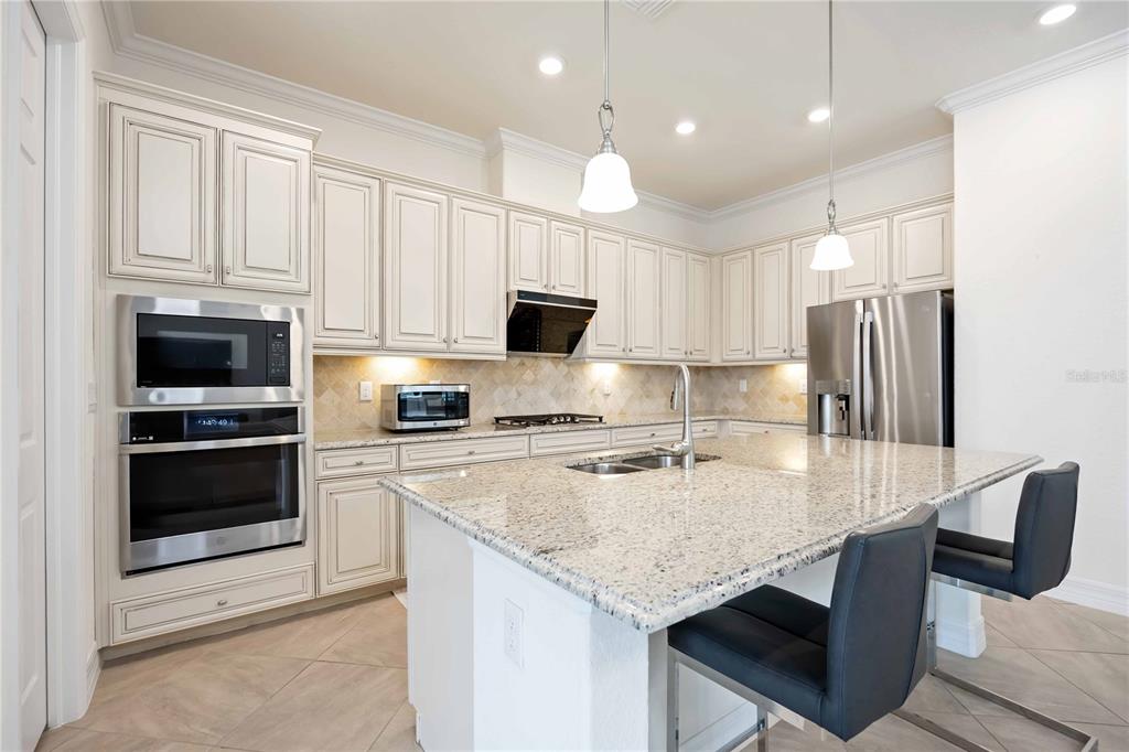 5931 Brandon Run Bradenton, FL 34211 - Photo 11 of 42 a kitchen with kitchen island granite countertop a stove sink microwave and refrigerator