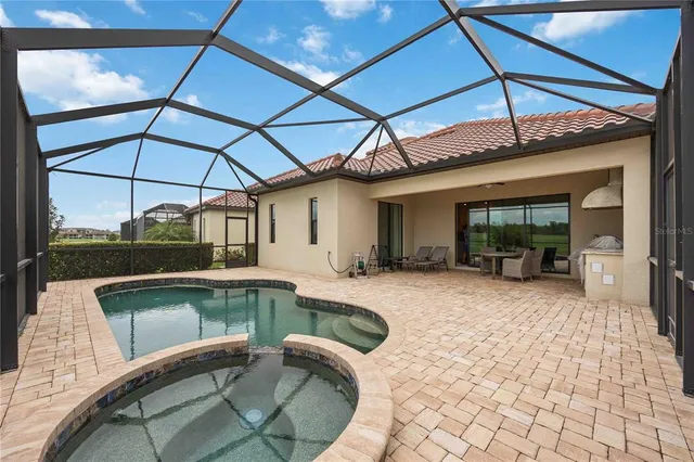 a swimming pool with barbeque oven table and chairs under an umbrella