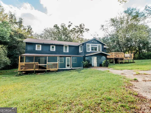 a view of a house with a big yard and large trees