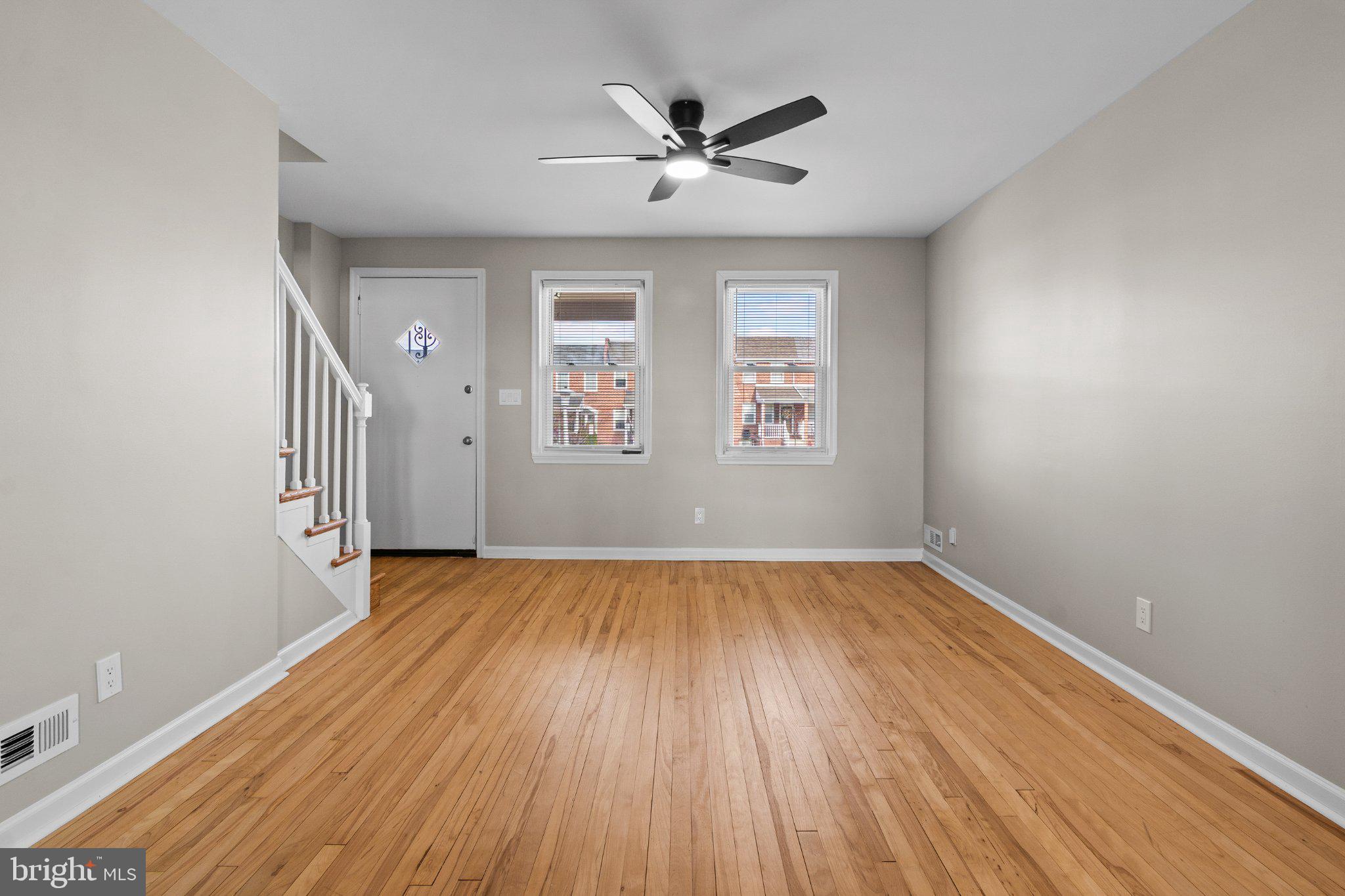 6929 Bank Street Baltimore, MD 21224 - Photo 12 of 30 an empty room with wooden floor a ceiling fan and windows