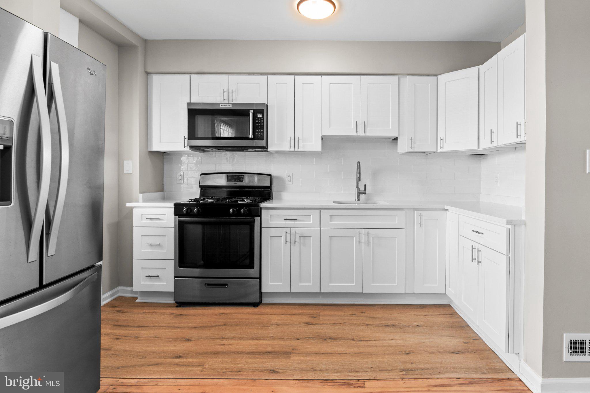 6929 Bank Street Baltimore, MD 21224 - Photo 2 of 30 a kitchen with white cabinets and stainless steel appliances