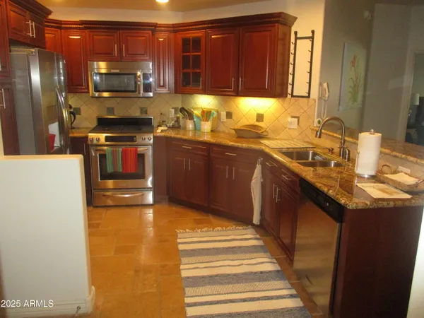 a kitchen with stainless steel appliances granite countertop a sink stove and refrigerator