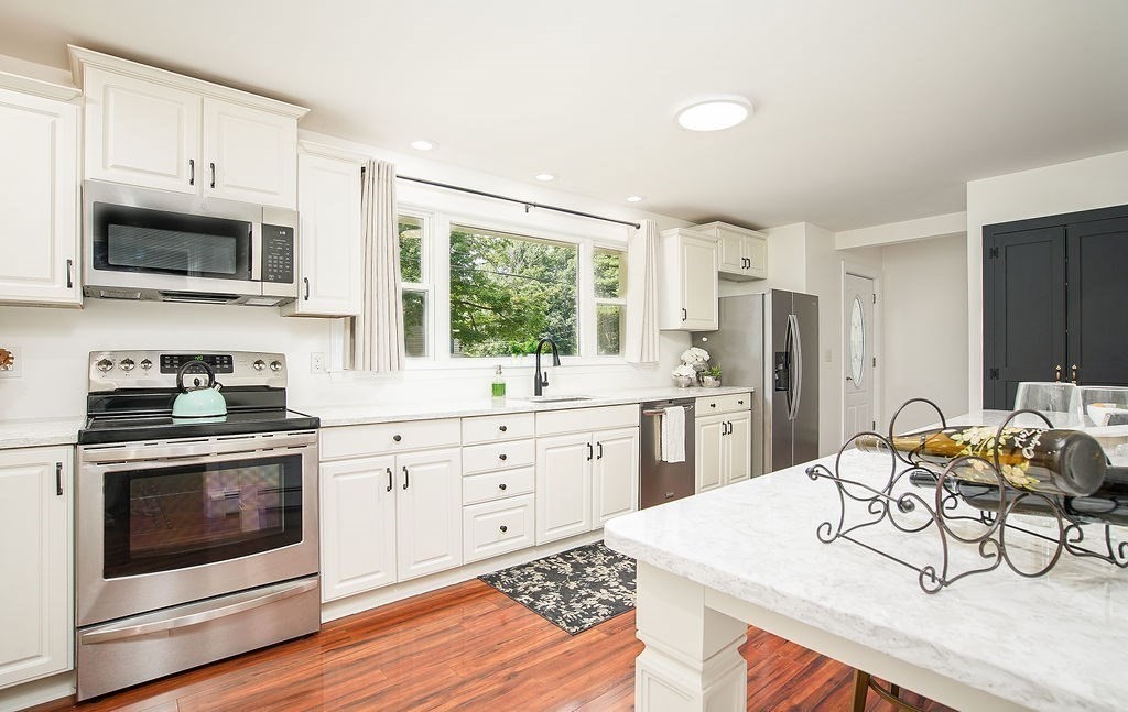84 Clark Road Sturbridge, MA 01518 - Photo 7 of 30 a kitchen with stainless steel appliances kitchen island granite countertop a stove a sink dishwasher a microwave oven with white cabinets and wooden floor