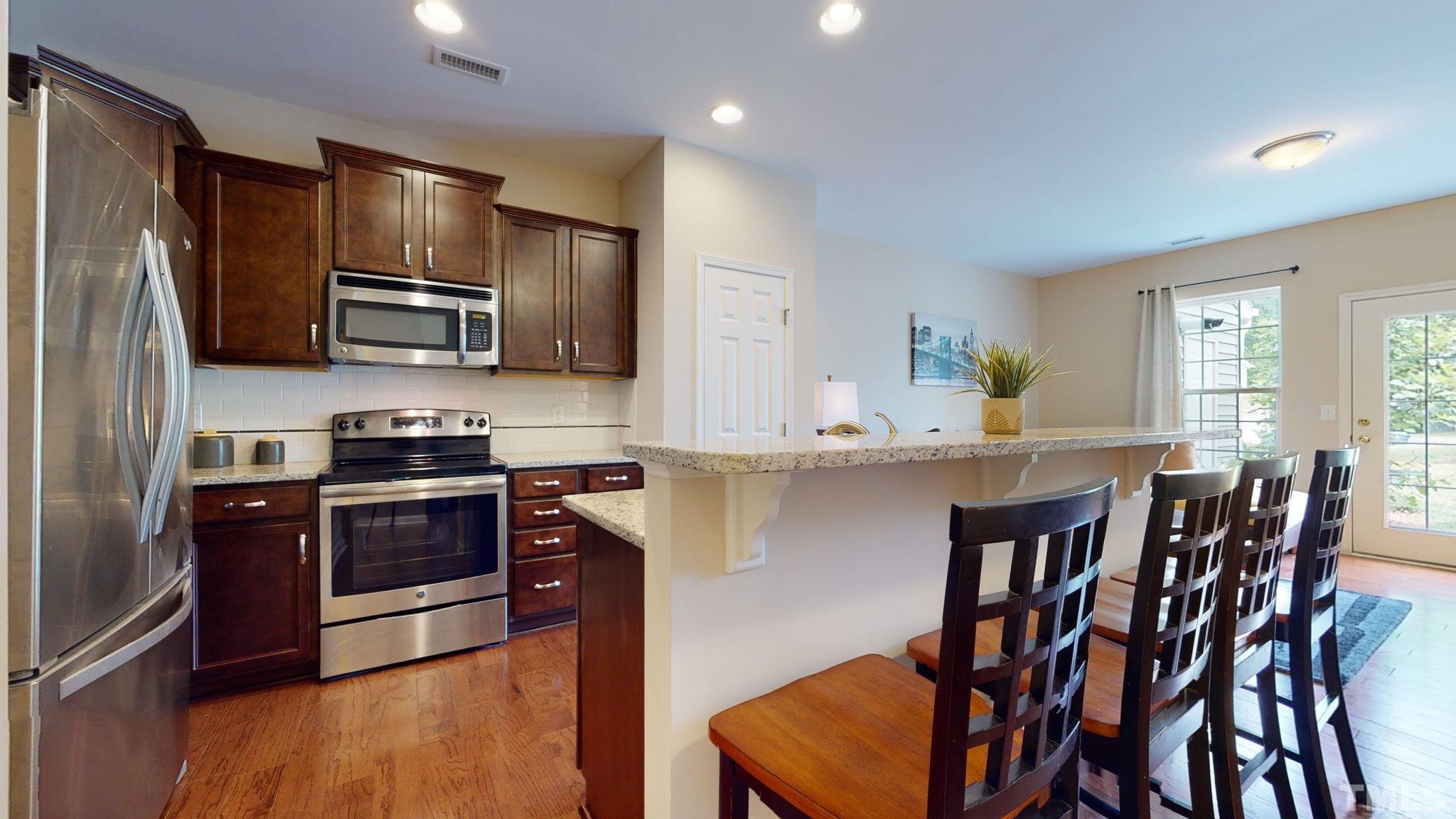 944 Consortium Drive Raleigh, NC 27603 - Photo 17 of 30 a kitchen with stainless steel appliances granite countertop a stove a sink a microwave a refrigerator and island