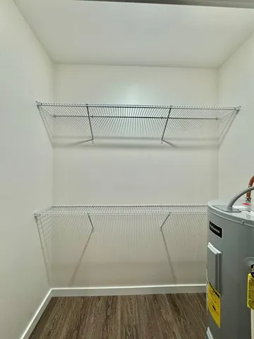 an empty room with wooden floor cabinet and windows