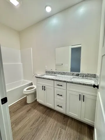 a bathroom with a granite countertop window a toilet and a bathtub