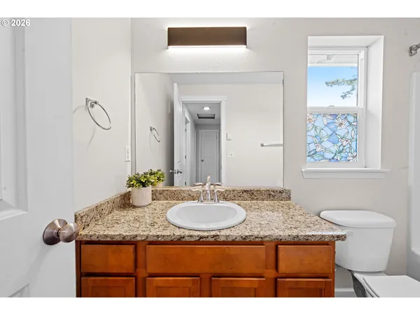 a bathroom with a granite countertop sink toilet a mirror and a tub