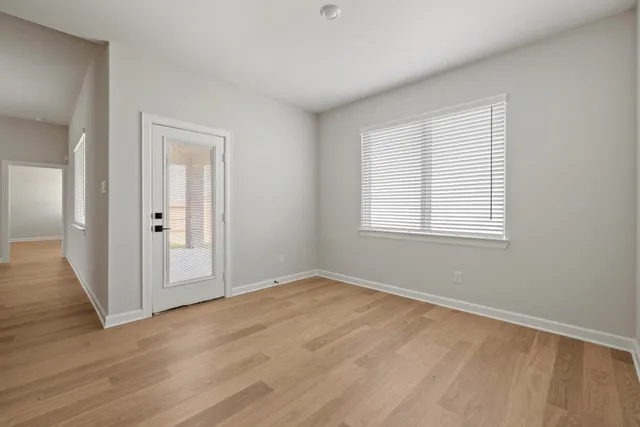 a view of an empty room with wooden floor and a window