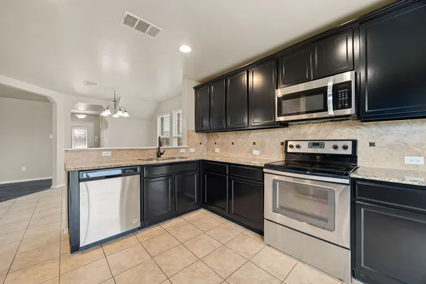 a kitchen with stainless steel appliances kitchen island granite countertop a stove sink and cabinets