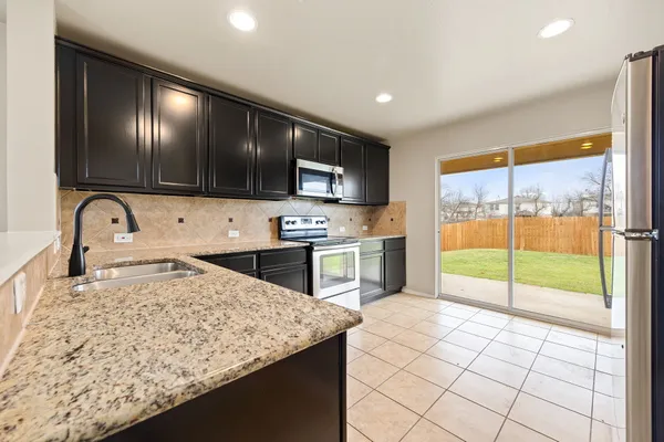 a kitchen with granite countertop a stove a sink and a microwave
