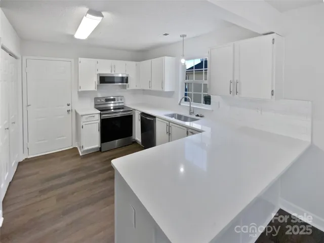 a large kitchen with cabinets wooden floor and stainless steel appliances