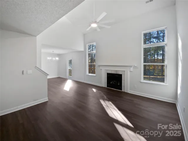 a view of a livingroom with wooden floor a fireplace and windows