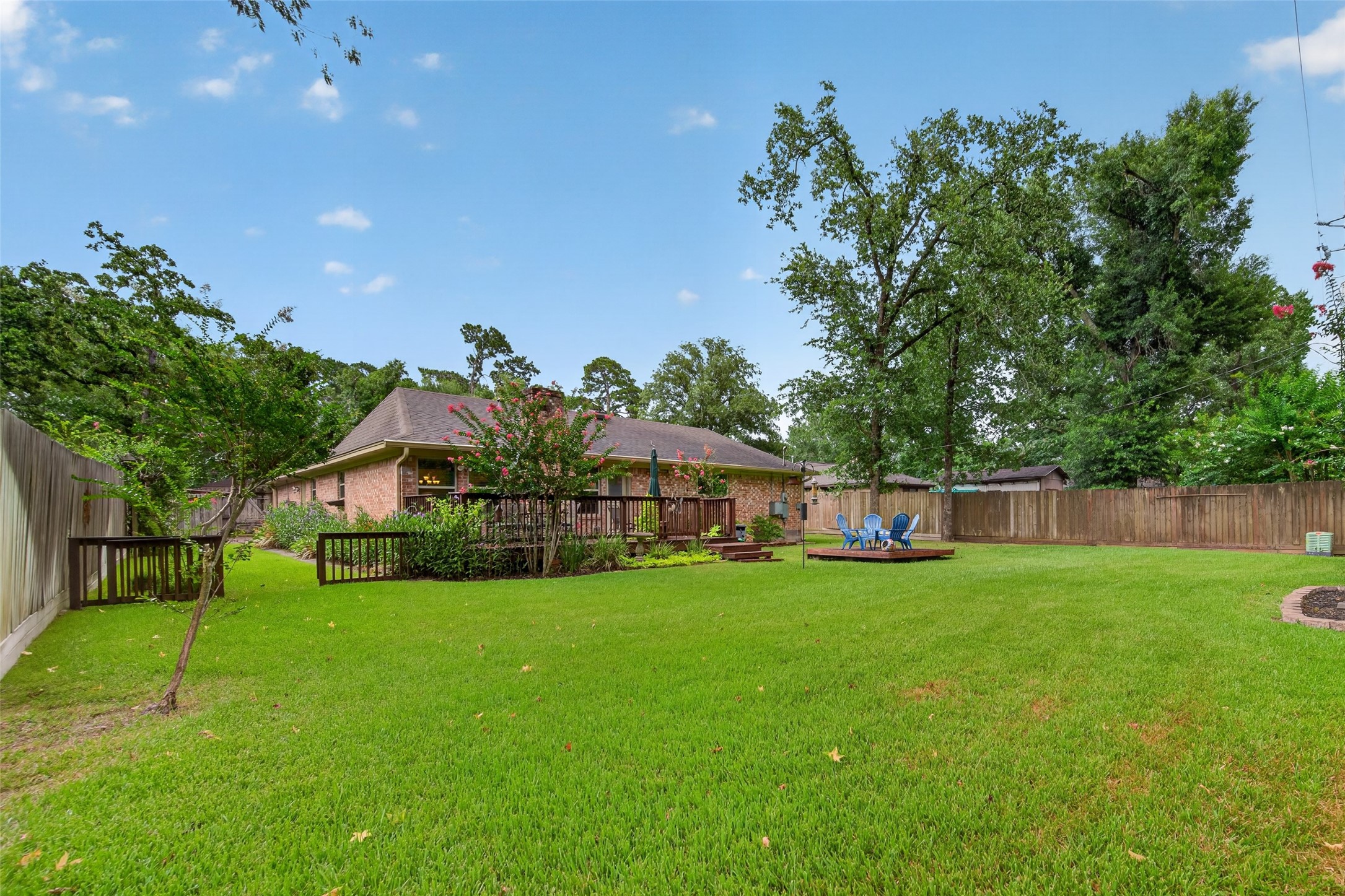 24719 Wilderness Road Spring, TX 77380 - Photo 41 of 42 Spacious backyard featuring a well-maintained lawn, a wooden deck with seating, and a privacy fence. Ideal for outdoor activities and relaxation.