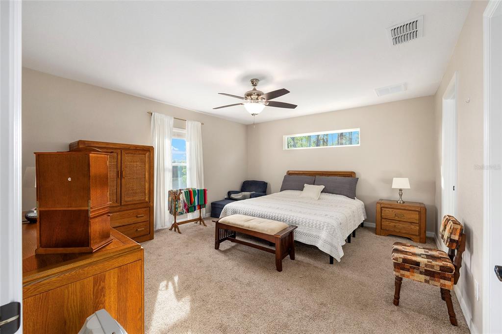 13057 Southwest 85th Circle Ocala, FL 34473 - Photo 11 of 34 a bedroom with a bed and a chandelier