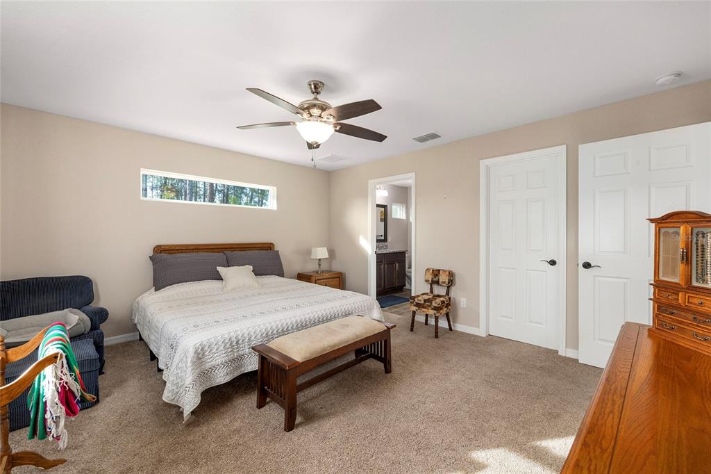 13057 Southwest 85th Circle Ocala, FL 34473 - Photo 12 of 34 a bedroom with a bed and a chandelier