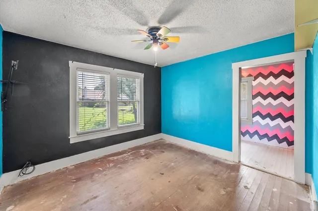 an empty room with window and chandelier fan