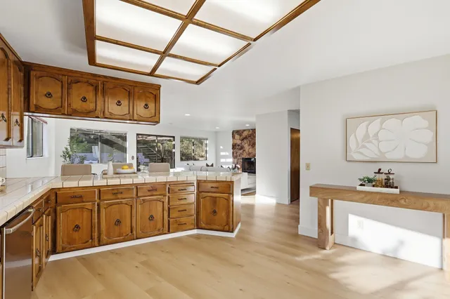 a kitchen with stainless steel appliances granite countertop a refrigerator a sink dishwasher a stove with wooden cabinets and floors